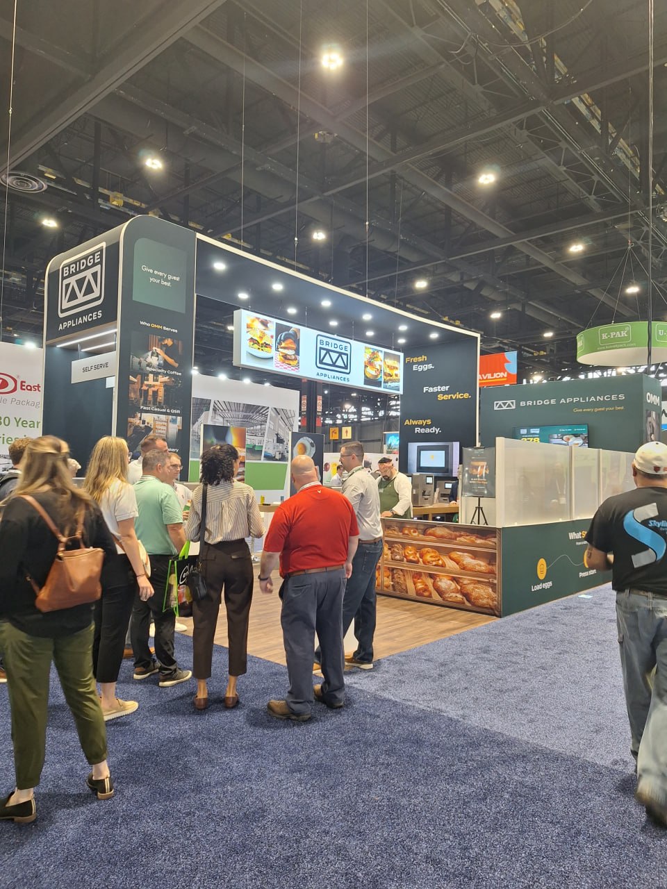 Trade show exhibit with an audience gathered around the booth